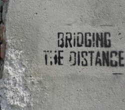 bridging the distance text on gray concrete surface close-up photography